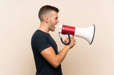 Izole arka plan üzerinde genç yakışıklı sarışın adam bir megafon ile bağırarak