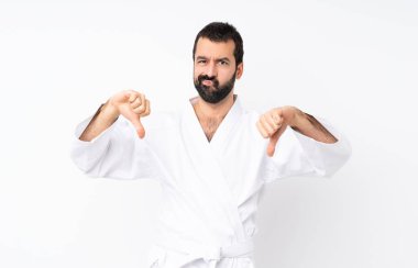 Young man doing karate over isolated white background showing thumb down