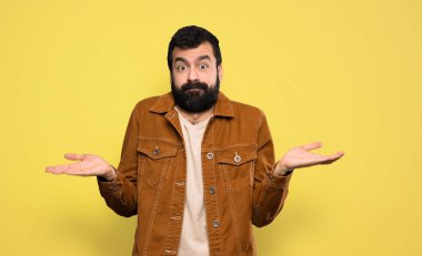 Handsome man with beard having doubts while raising hands