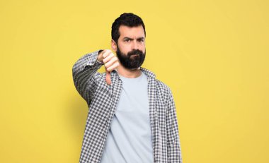 Handsome man with beard showing thumb down with negative expression