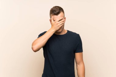 İzole edilmiş arka planda genç, yakışıklı sarışın adam gözleri elleriyle kapatıyor. Bir şey görmek istemiyorum.