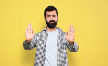 Handsome man with beard making stop gesture and disappointed