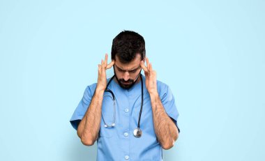 Surgeon doctor man with headache over isolated blue background