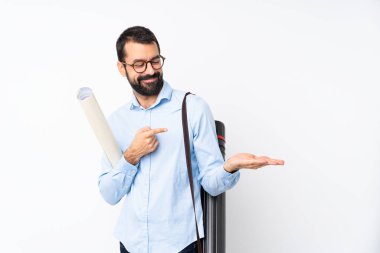 Young architect man with beard over isolated white background holding copyspace imaginary on the palm to insert an ad