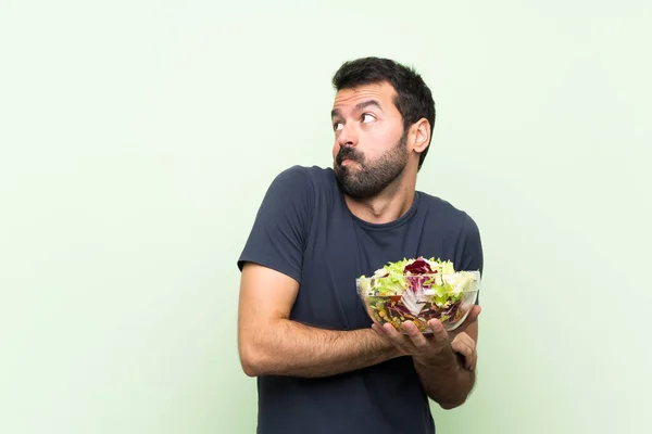 Jovem Homem Bonito Com Salada Sobre Parede Verde Isolada Fazendo — Fotografia de Stock