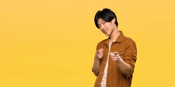 Азіатський Чоловік Коричневою Курткою Вказує Спереду Посміхається Над Ізольованим Жовтим — стокове фото