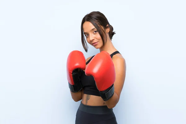 Jovem menina esporte com luvas de boxe sobre fundo azul isolado — Fotografia de Stock