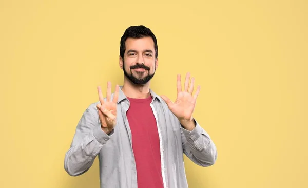 Красивий Чоловік Бородою Рахуючи Вісім Пальцями Над Ізольованим Жовтим Тлом — стокове фото