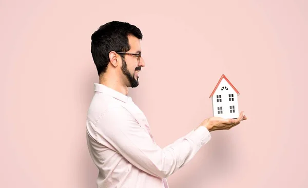 Handsome man with beard holding a little house — Stock Photo, Image