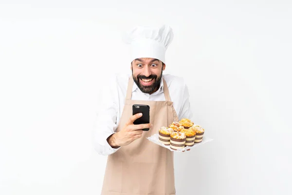 Junger Mann Mit Muffin Kuchen Vor Isoliertem Weißen Hintergrund Überrascht — Stockfoto