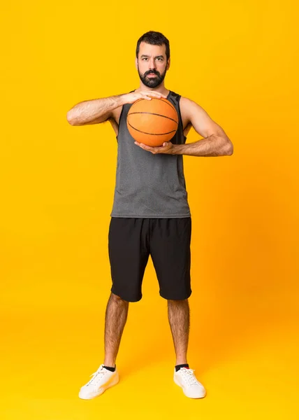 Tiro completo de um homem jogando basquete sobre fundo amarelo isolado — Fotografia de Stock