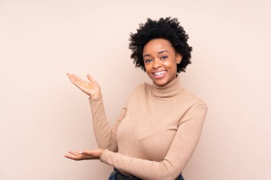 Afrika kökenli Amerikalı bir kadın, izole edilmiş arka planda, davet edildiği için ellerini yana uzatıyor.