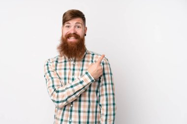 Uzun sakallı, soyutlanmış beyaz arkaplanı olan kızıl saçlı bir adam bir ürün sunmak için kenarı işaret ediyor.