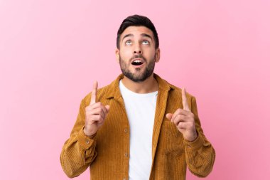 Pembe arka planda kadife ceket giyen sakallı yakışıklı genç adam işaret parmağıyla işaret etmek harika bir fikir.