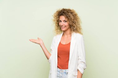 Sarışın, kıvırcık saçlı, izole edilmiş yeşil arka planı olan genç bir kadın.