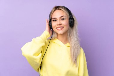 Soyutlanmış mor arka planda müzik dinleyen genç kız.