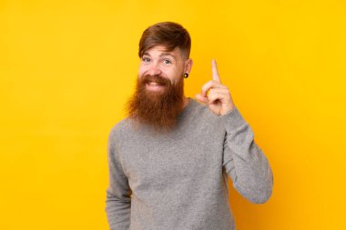 Sarı arka planda uzun sakallı kızıl saçlı adam en iyinin işareti olarak parmağını kaldırıyor.