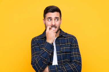 Sakallı yakışıklı genç adam izole edilmiş sarı arka planda gergin ve korkmuş.