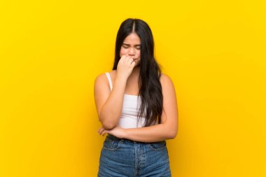 Young teenager Asian girl over isolated yellow background having doubts