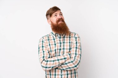 Uzun sakallı, soyutlanmış beyaz arka planı olan kızıl saçlı adam gülümserken yukarı bakıyor.