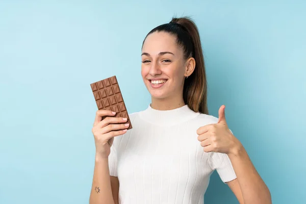 Young Brunette Woman Isolated Blue Background Taking Chocolate Tablet Thumb — 스톡 사진