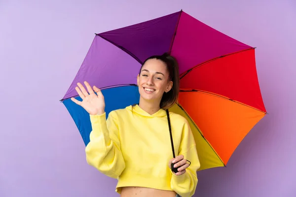 Jonge Brunette Vrouw Houden Een Paraplu Geïsoleerde Paarse Muur Salueren — Stockfoto