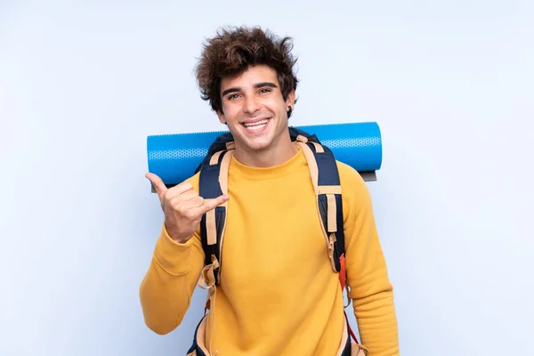 Ung Bergsklättrare Man Med Stor Ryggsäck Över Isolerad Blå Bakgrund — Stockfoto