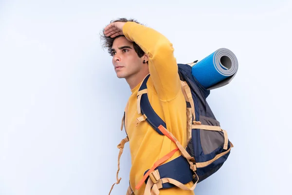 Joven Montañero Con Una Gran Mochila Sobre Fondo Azul Aislado — Foto de Stock