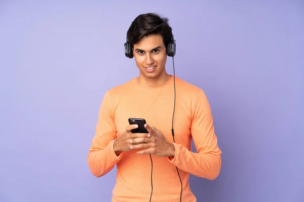 Homem Sobre Fundo Roxo Isolado Ouvir Música Com Celular Olhando — Fotografia de Stock