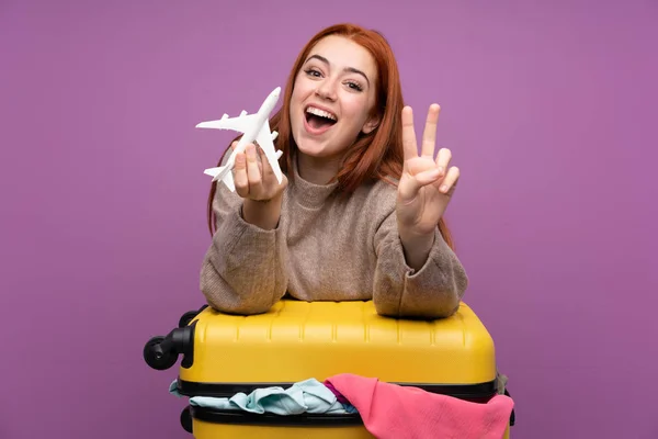 Podróżniczka z walizką pełną ubrań i trzymająca zabawkę w samolocie — Zdjęcie stockowe