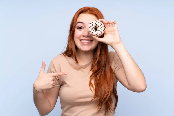 Rotschopf Teenager Mädchen Über Isolierten Blauen Hintergrund Hält Einen Donut — Stockfoto