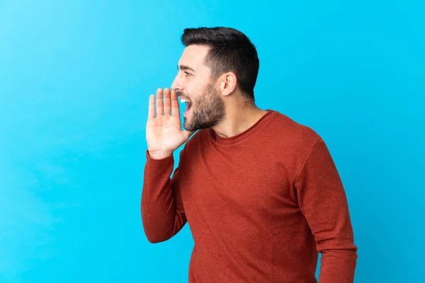 Jovem Homem Bonito Com Barba Sobre Fundo Azul Isolado Gritando — Fotografia de Stock