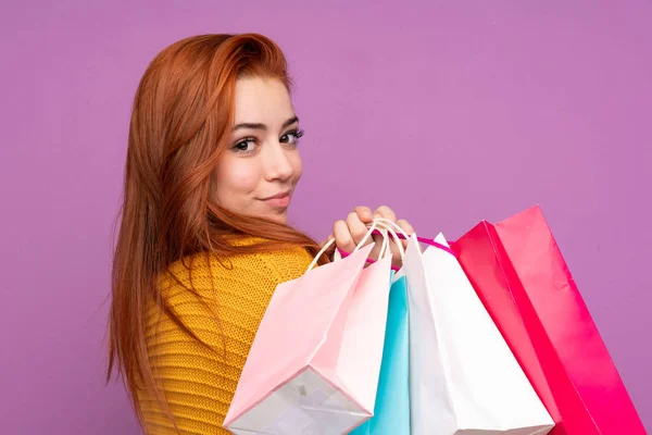 Redhead Teenager Girl Isolated Purple Background Holding Shopping Bags — 스톡 사진