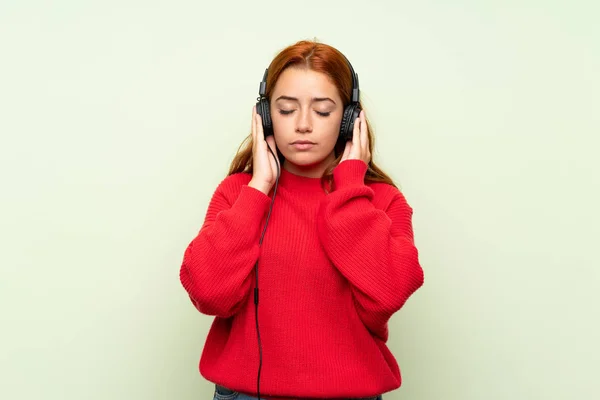Έφηβος Κοκκινομάλλα Κορίτσι Πουλόβερ Πάνω Από Απομονωμένο Πράσινο Φόντο Ακούγοντας — Φωτογραφία Αρχείου