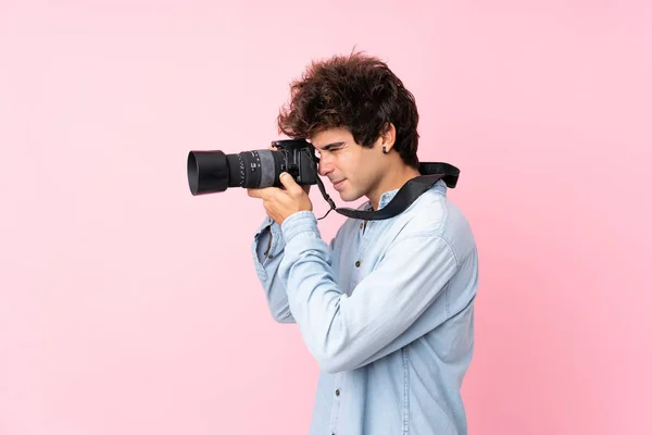 Jovem Caucasiano Sobre Fundo Rosa Isolado Com Uma Câmera Profissional — Fotografia de Stock