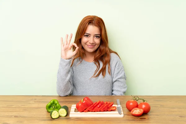 Nastoletnia Ruda Dziewczyna Warzywami Stole Pokazującym Znak Palcami — Zdjęcie stockowe