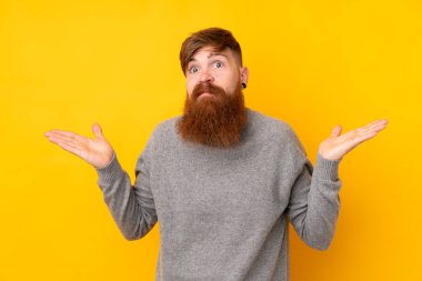 Kızıl saçlı, uzun sakallı, izole edilmiş sarı arka planda şüpheli hareketler yapan bir adam.