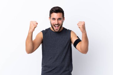 Sakallı yakışıklı genç adam izole edilmiş beyaz arka plan zaferi kutluyor.