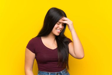 Izole sarı arka plan üzerinde genç genç Asyalı kız gülüyor