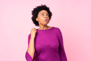 Yorgun ve hasta bir ifadeyle izole edilmiş pembe arka planı olan Afrikalı Amerikalı bir kadın.