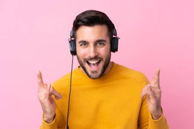 Sakallı yakışıklı genç adam soyutlanmış pembe müzik dinliyor.