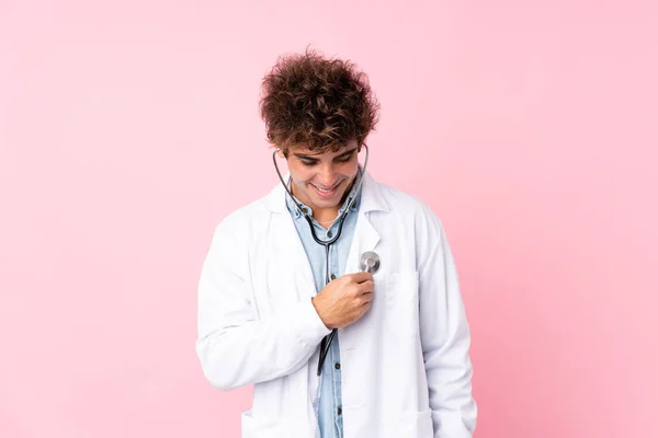 年轻的高加索男子与孤立的粉红色背景与医生礼服 — 图库照片
