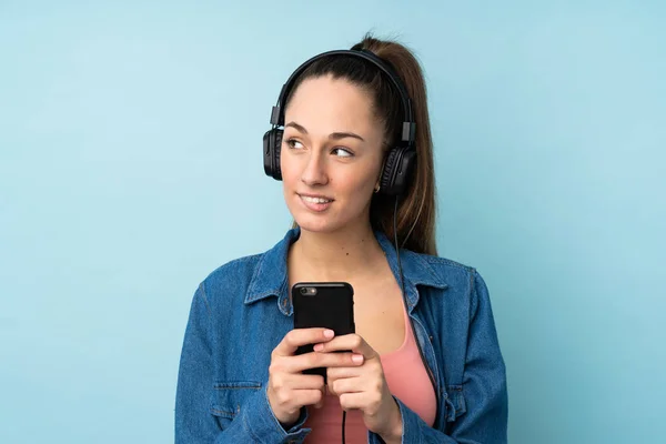 Giovane Donna Bruna Sfondo Blu Isolato Ascoltare Musica Con Cellulare — Foto Stock