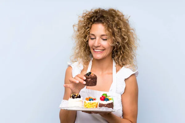 젊은 금발의 여자 와 곱슬 머리 들고 많은 의 다른 미니 케이크 — 스톡 사진