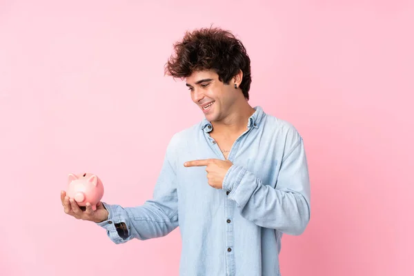 Joven Caucásico Hombre Sobre Aislado Rosa Fondo Holding Grande Piggybank —  Fotos de Stock