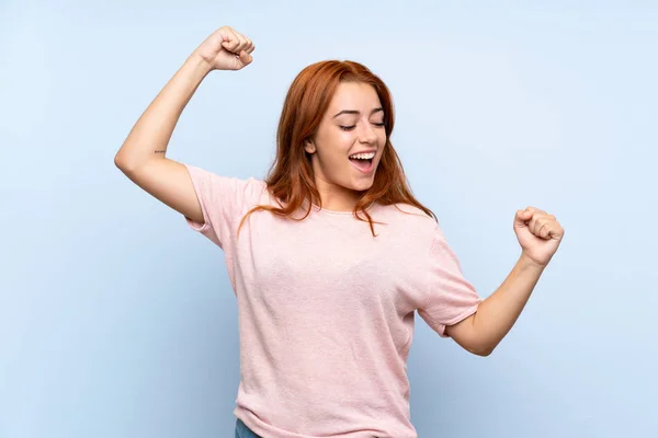 Tiener Roodharige Meisje Geïsoleerde Blauwe Achtergrond Vieren Een Overwinning — Stockfoto