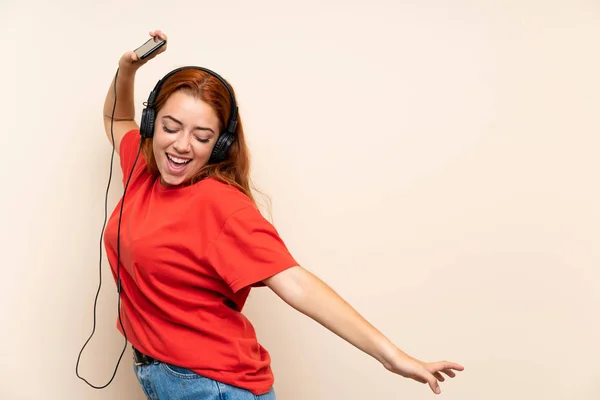 孤立した背景の上に音楽を聴くティーンエイジャー赤毛の女の子 — ストック写真