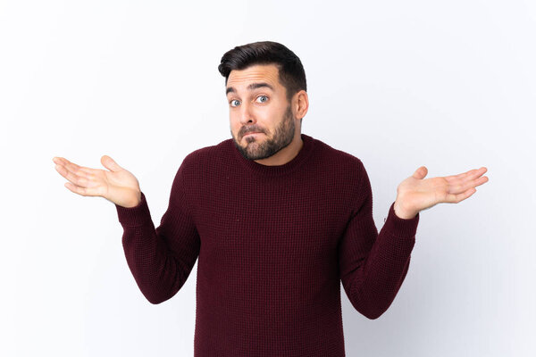 Young handsome man with beard over isolated white background having doubts while raising hands