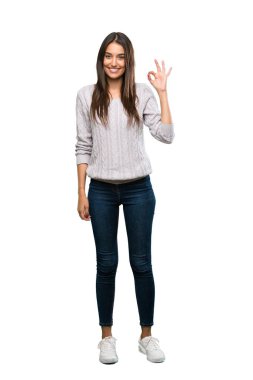 A full-length shot of a Young hispanic brunette woman showing ok sign with fingers over isolated white background