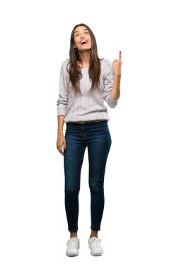 A full-length shot of a Young hispanic brunette woman pointing up and surprised over isolated white background